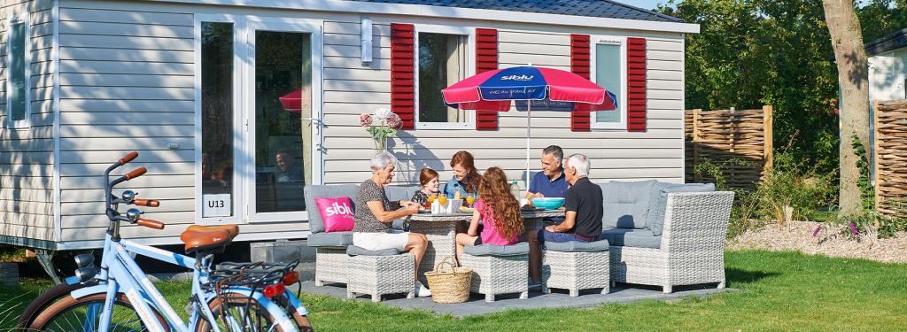 Famille déjeune sur la terrasse de son mobil home au camping de Oase